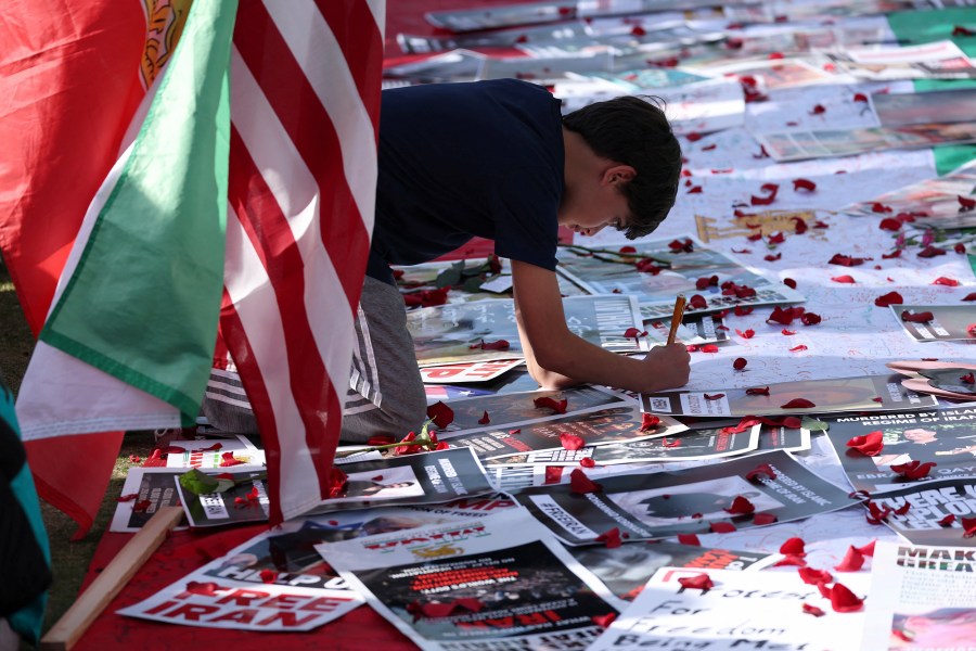 A young boy signs a poster on the ground during a demonstration.