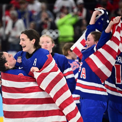 Hockey players in jerseys that read "USA" celebrate with American flags.