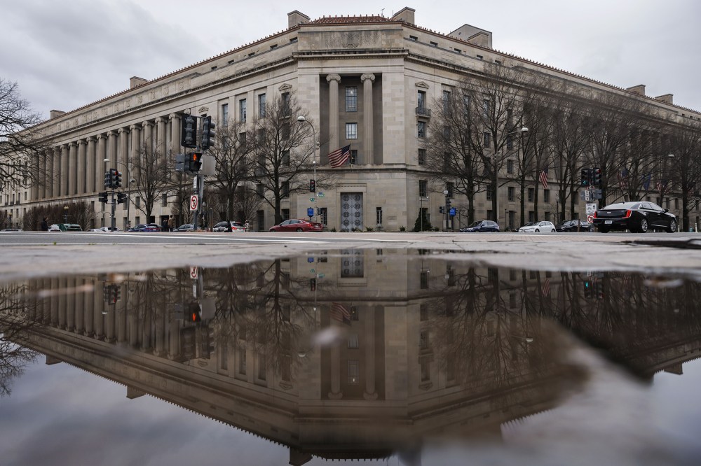 The Department of Justice building, seen reflected in a puddle.