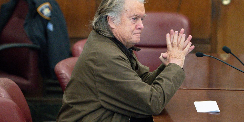 Steve Bannon sits at a desk.