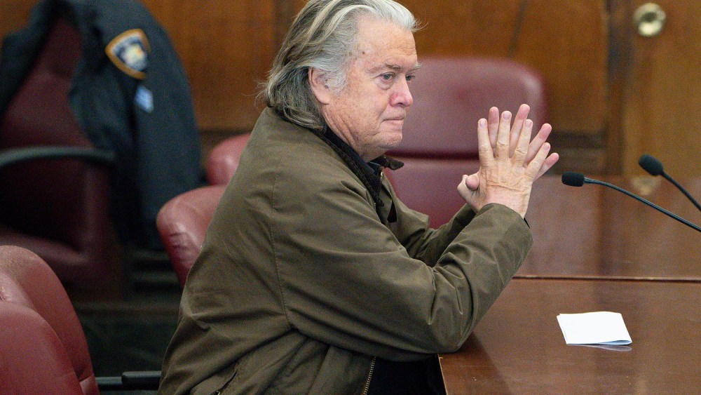 Steve Bannon sits at a desk.