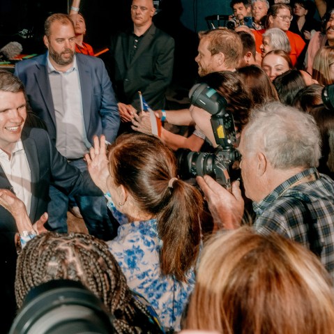 James Talarico, left, is about to hug a supporter while a crowd is cheering for him.