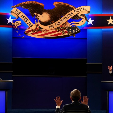 Donald Trump, left, and Joe Biden, right, raise their hands as they speak.