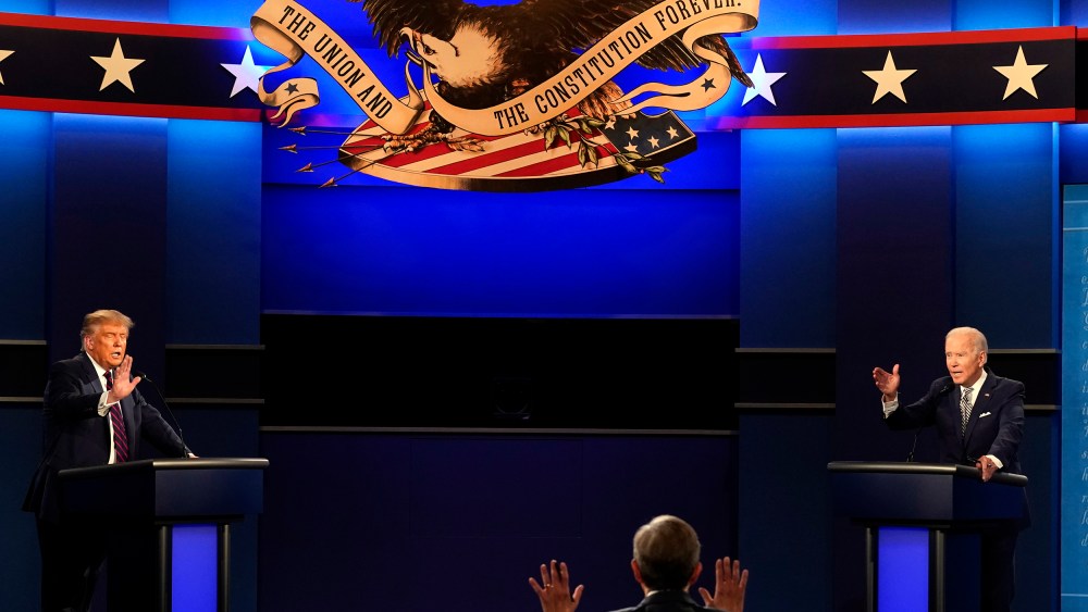 Donald Trump, left, and Joe Biden, right, raise their hands as they speak.