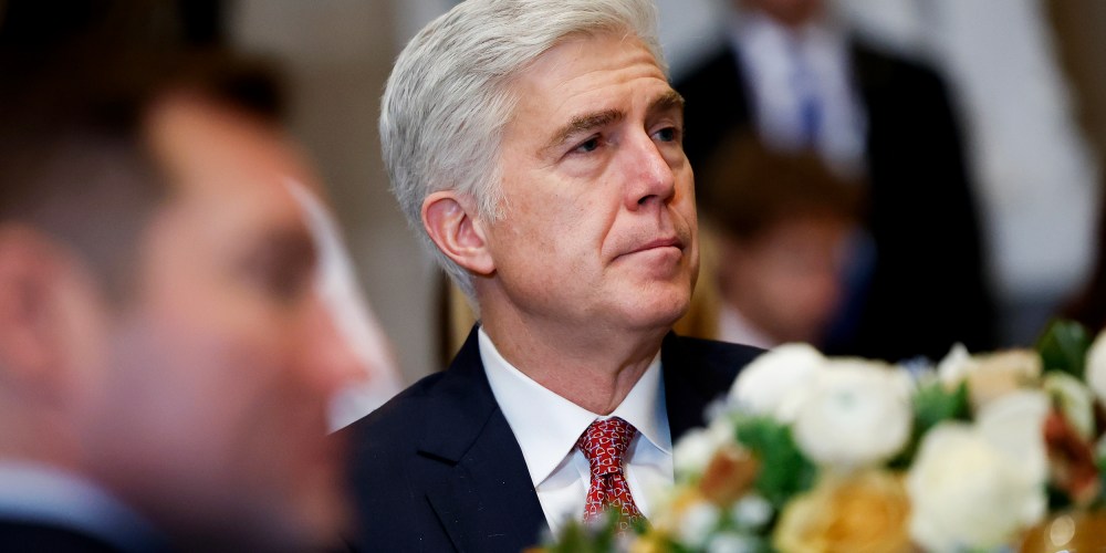 Neil Gorsuch looks on as he sits at a table with other people.