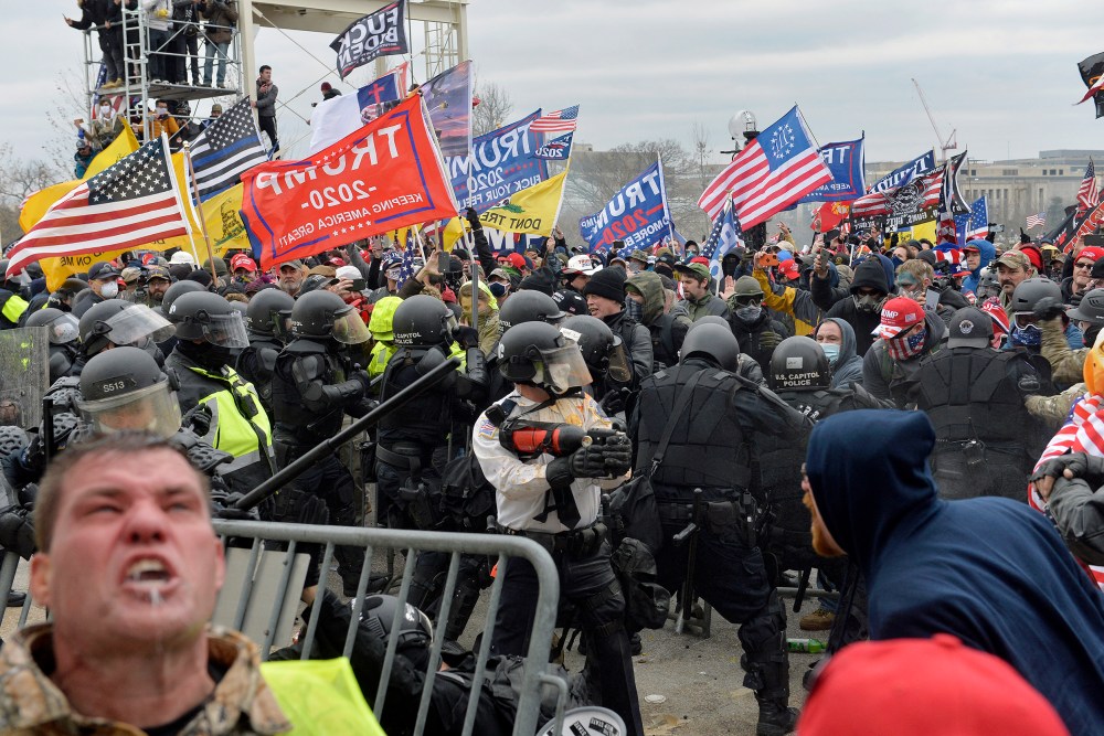 A man seen screaming in the foreground as other protestors clash with law enforcement.