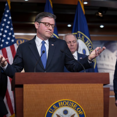 Mike Johnson gestures behind a podium.