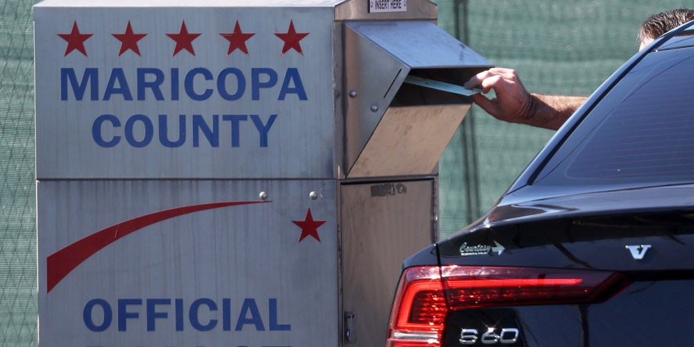 A voter drops their ballot into a drop box outside of the Maricopa County Tabulation and Election Center in Phoenix.