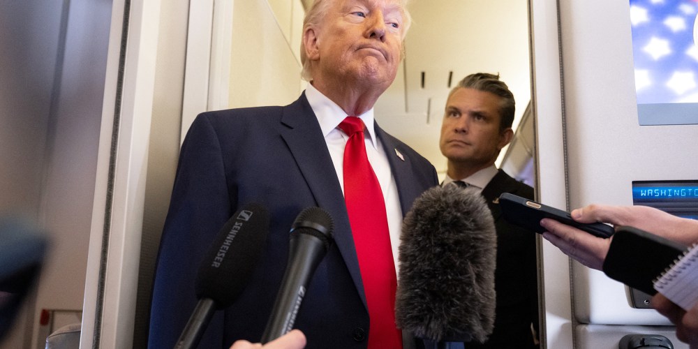 President Donald Trump speaks with the media as Defense Secretary Pete Hegseth looks on aboard Air Force One.