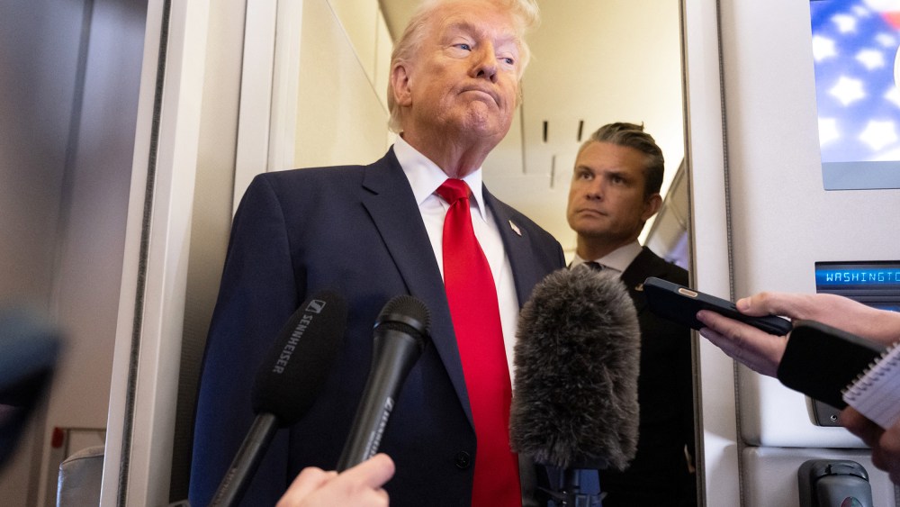 President Donald Trump speaks with the media as Defense Secretary Pete Hegseth looks on aboard Air Force One.