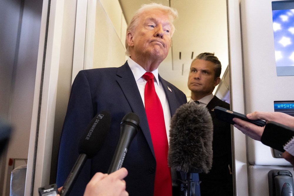 President Donald Trump speaks with the media as Defense Secretary Pete Hegseth looks on aboard Air Force One.