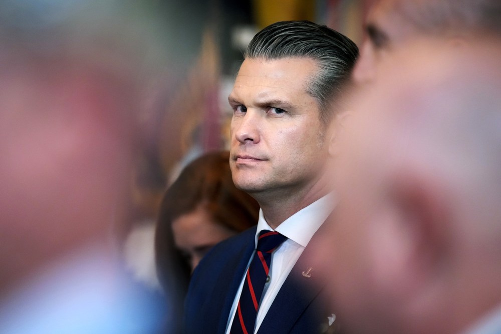 Pege Hegseth’s profile can be seen among other people who are out of focus.